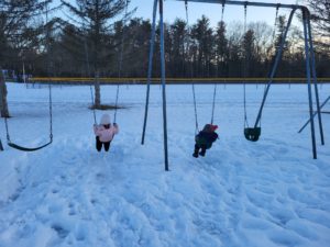 Kids playing on swings in the snow